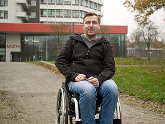 Junger Mann sitzt im Rollstuhl