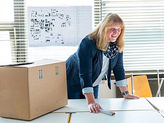Heike Hemmersbach Heike Hemmersbach leans over a table, in the background a room plan
