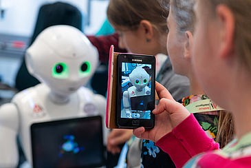 Display eines Smartphones zeigt kleinen Roboter
