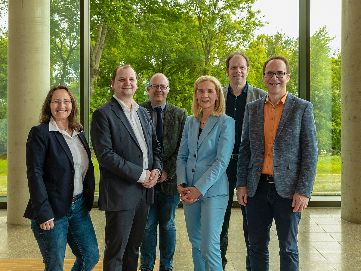 Historischer Erfolg: Uni Bremen wirbt erstmalig zwei Exzellenzcluster ein Forscher:innen und Leitung der Universität Bremen stehen nebeneinander in einem Foyer.