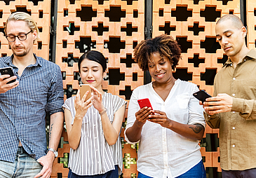 Zwei Frauen und zwei Männer, die auf ihre Smartphones schauen