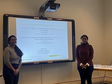 Yamani (left) and Sowmia (right) stand in front of their PowerPoint presentation