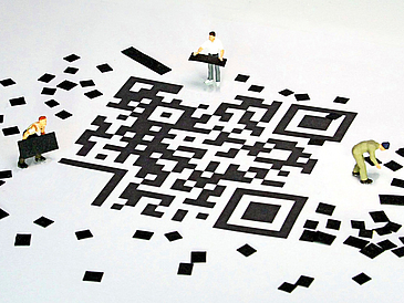 QR-Code mit kleinen Figuren, die kleine Schnipsel herumtragen