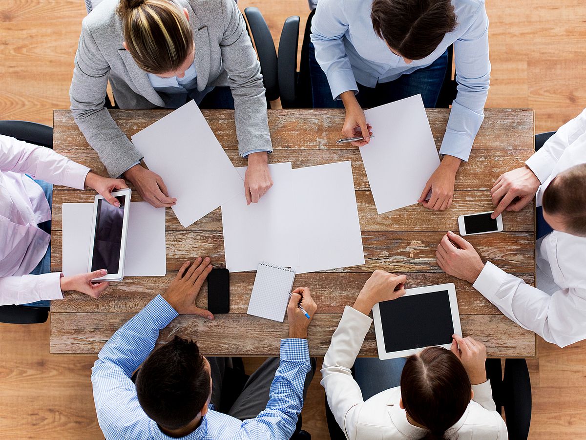 Management & Future Skills Gruppe von Geschäftsleuten mit Smartphones und Tablets an einem Tisch