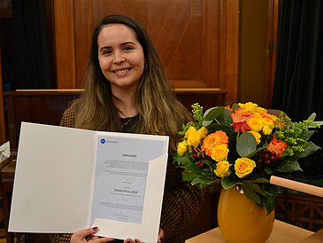 Jody Danard mit der Urkunde des DAAD-Preises und einem Blumenstrauß