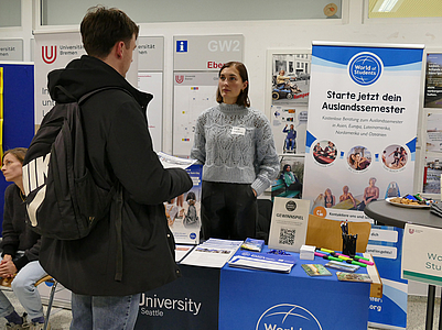 Ein Student an einem Infostand sprich mit der Ausstellerin