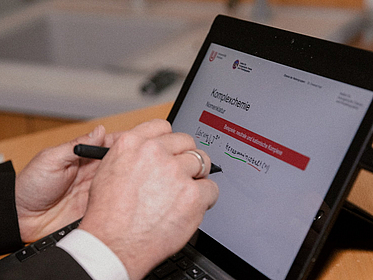 Eine Hand schreibt auf einem Tablet