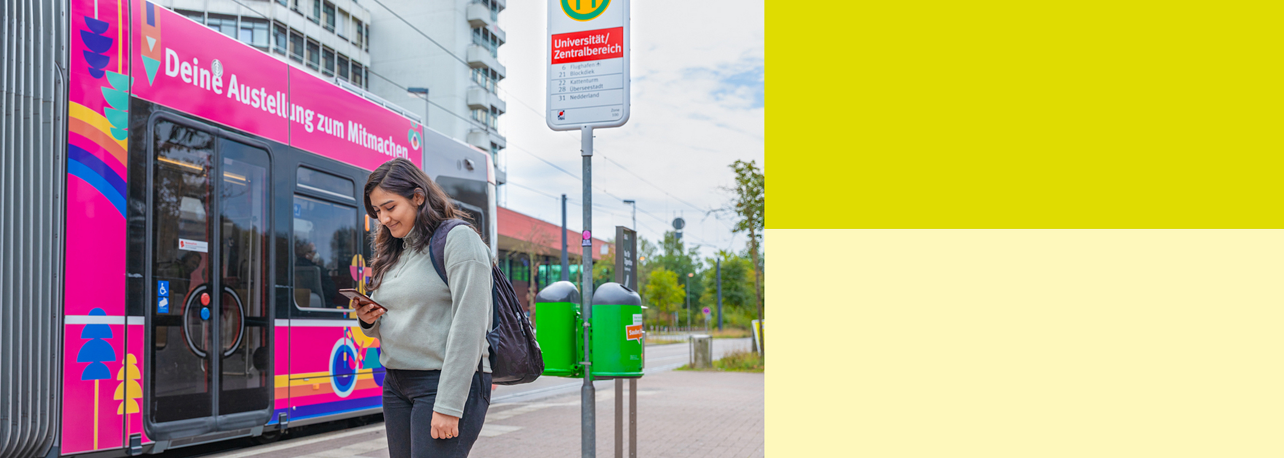 Frau steht an Straßenbahnhaltestelle.