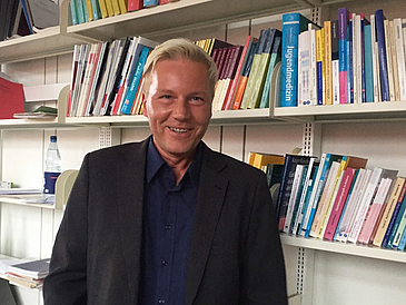 Professor Christian Palentien vor einer Bücherwand