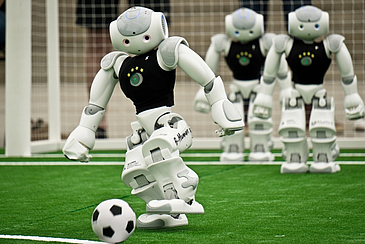 Drei Fußballroboter in Aktion