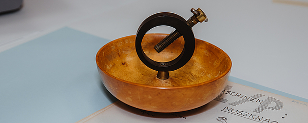 KennenSieSchon_Uni-Archiv_MatejMeza Ein Nussknacker aus Holz steht auf einem Tisch, auf dem auch eine Anleitung liegt.