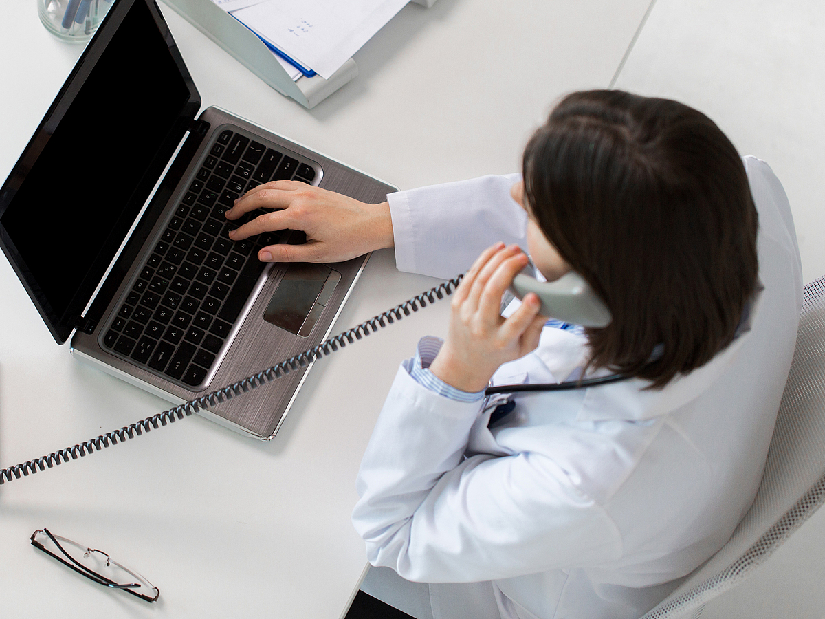 Ärztin am Telefon mit Laptop