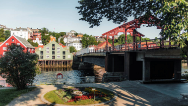 IFAC 2025 Ein Fluss hinter dem Häuser stehen. Auf der rechten Seite ist eine Brücke zum überqueren des Flusses.