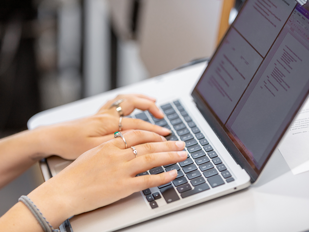 NEU: Video-basierte KI-Selbstlernkurse Zu sehen ist ein Laptop, auf welchem gerade Mitschriften während einer Vorlesung gemacht werden