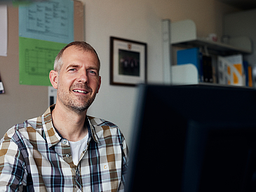 Scientist Norman Sieroka sits at a desk in his office.