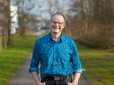 Porträtfoto von Stephan Determann, im Hintergrund ein Weg mit Wiese