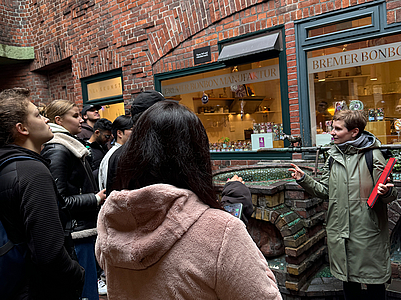 Stadtführerin erklärt den Austauschstudierende die Sehenswürdigkeiten in der Böttcherstraße in Bremen