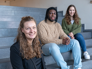 Studenten, die nebeneinander auf der Treppe sitzen