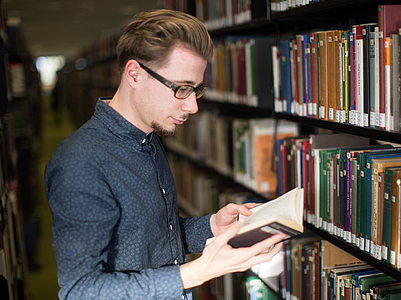 Ein Besucher der Bibliothek blättert in einem Buch.