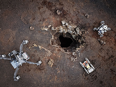 Ein Bild von Robotern die rund um einen Höhleneingang stehen