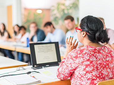 Frau spricht zu Studierenden