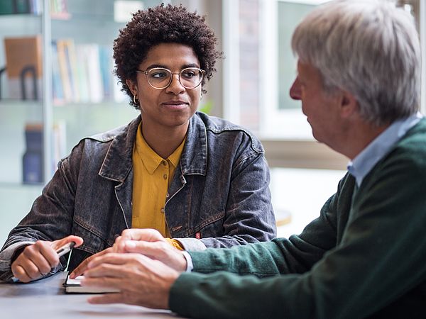 Eine Studentin und ein Seniorenstudent im Gespräch.