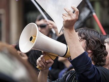 Demonstranten mit Megaphon und Notizbuch protestieren