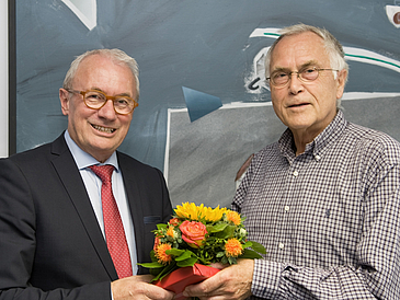 Zwei Männer halten einen Blumenstrauß und lächeln in die Kamera