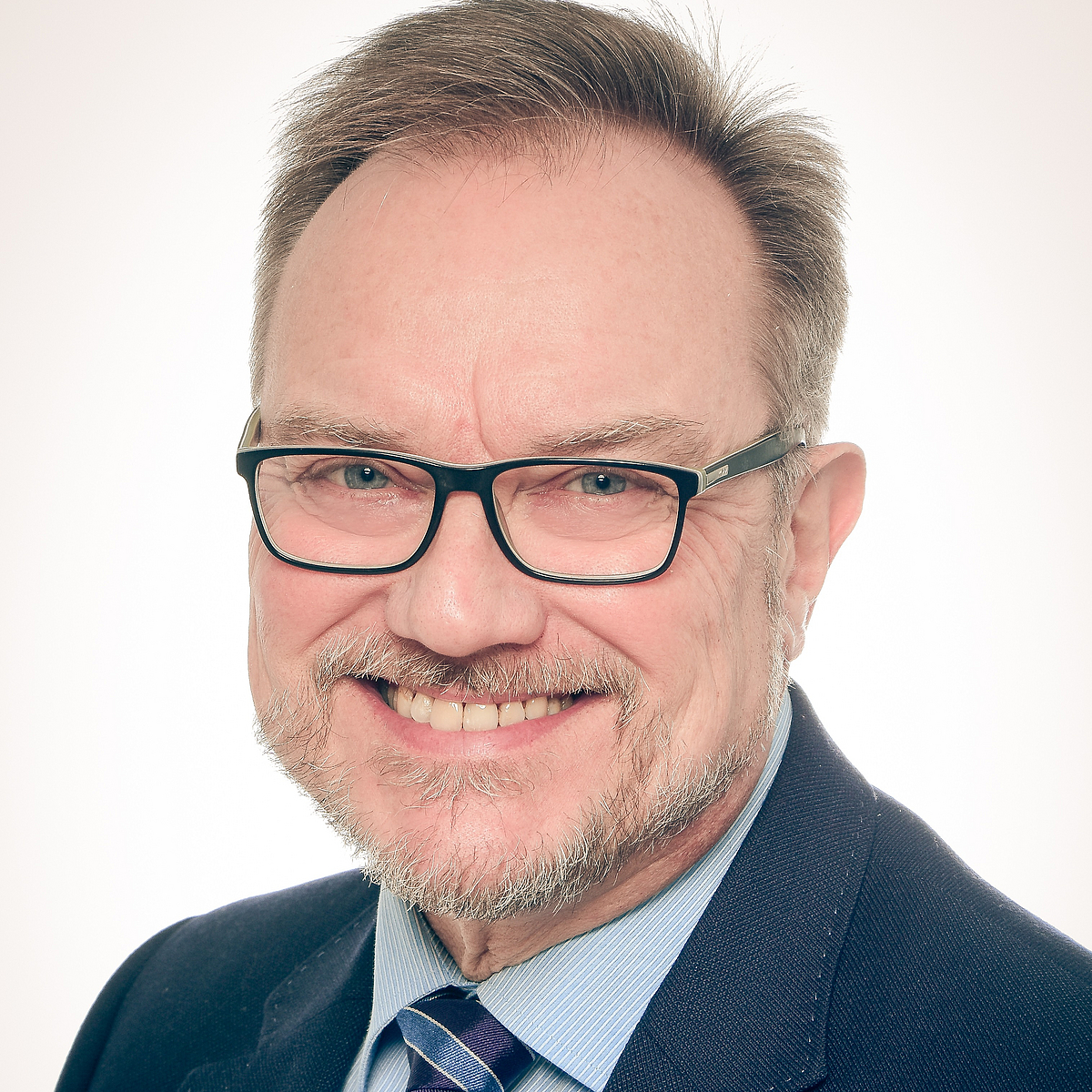 Foto von Herrn Professor Doktor Martin Missong, der sympathisch in die Kamera lächelt, bekleidet mit blauem Anzug und gestreifter Krawatte.