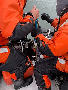 Two people taking sediment samples from a zodiac.