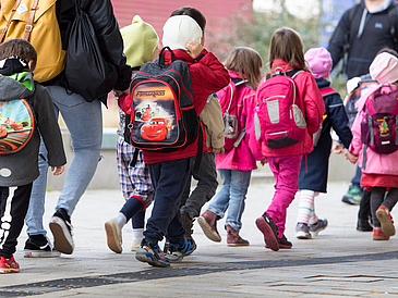 Eine Gruppe von Kleinkindern mit bunten Jacken und Rucksäcken.