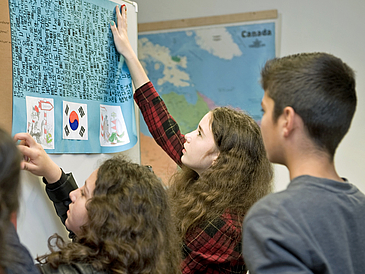 Schüler heften Plakat an eine Stellwand