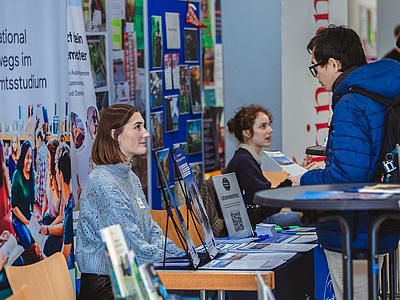 Zwei Frauen und ein Man unterhalten sich an einem Infostand