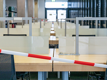 Absperrband vor Arbeitsplätzen in der Bibliothek.