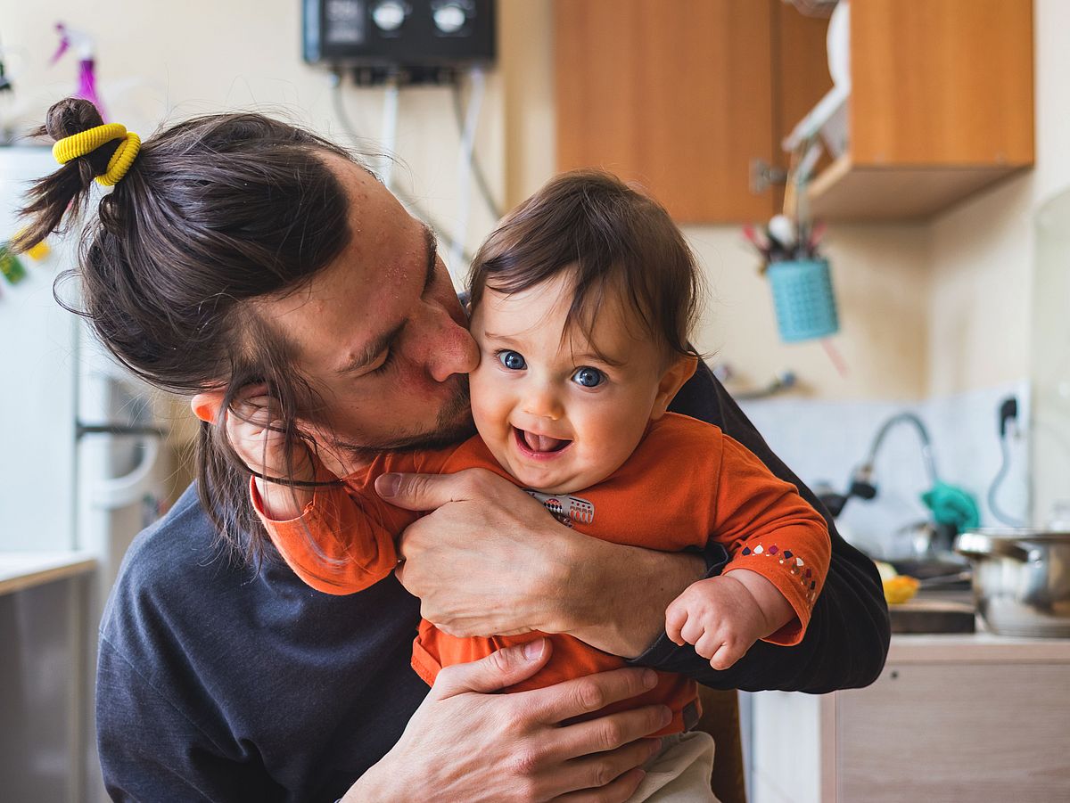 Hipster young father hug and kiss his baby infant boy holding on Student mit Kind