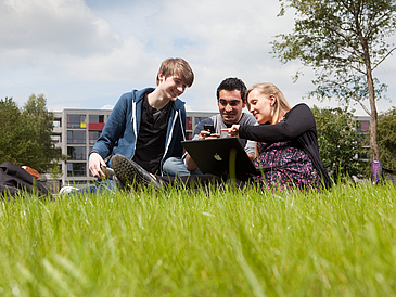 Schüler:innen mit Laptop auf einer Wiese