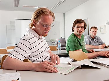 Drei Studierende beim Lernen in einem Seminarraum