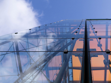 Ausschnitt der Glashalle vor blauem, leicht bewölktem Himmel.