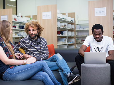 Studierende im Gespräch in der Bibliothek.