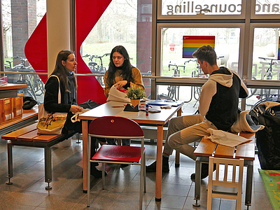 Studierende sitzen am Tisch am Welcome Desk