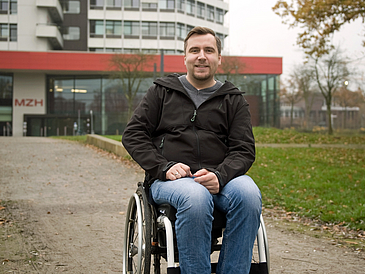 Junger Mann sitzt im Rollstuhl