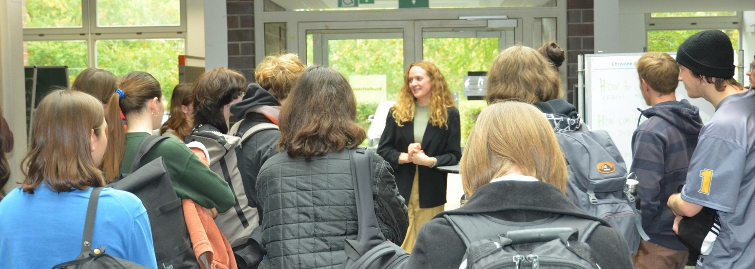 Dekoratives Bild mit Studierenden von hinten, die während der Auftaktveranstaltung mit Christine Falta diskutieren