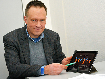 Mann mit Tablet lächelt in die Kamera