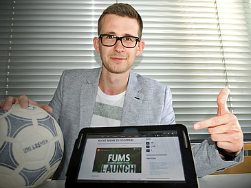 Junger Mann mit Fußball und Tablet-PC.