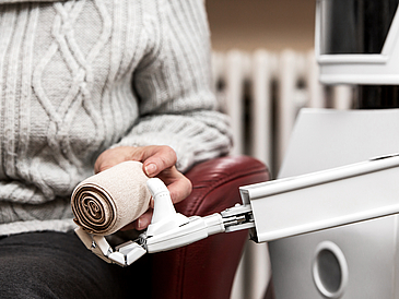 autonomous caregiver robot is holding a elastic bandage, giving it to an senior adult woman