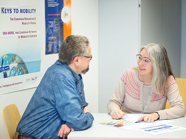 Zwei Personen im Gespräch an einem Tisch.