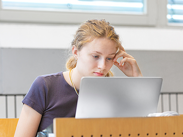 A student is looking at her laptop during a lecture