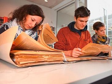 Geschichtsstudierende recherchieren in historischen Akten als Vorbereitung der szenischen Lesung