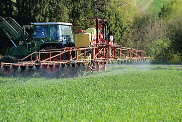 Traktor spritzt Pestizide in einem Feld