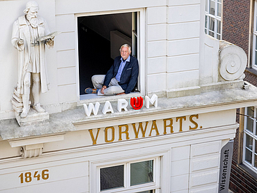 A Picture of the Building. The Building Chairman sitting in a window.